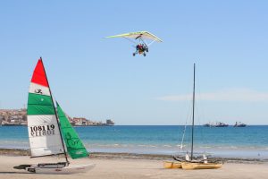 Two boats on a beach with air glider flying